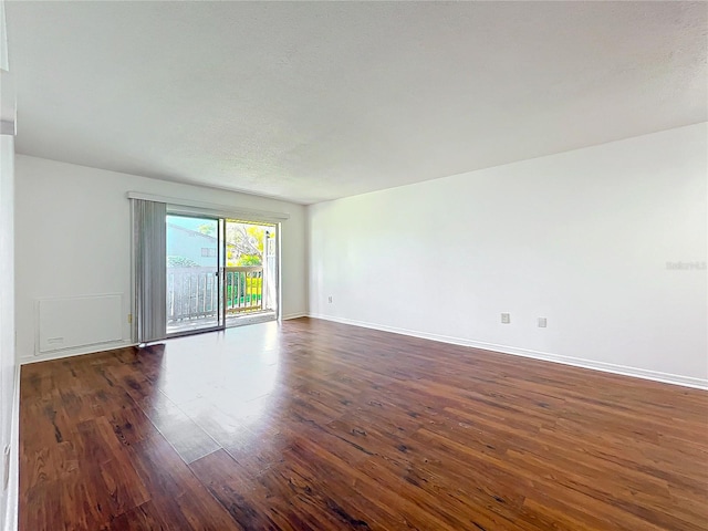 spare room with dark wood-style floors, a textured ceiling, and baseboards