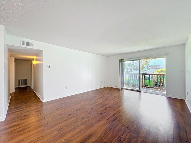 spare room with wood finished floors, visible vents, and baseboards