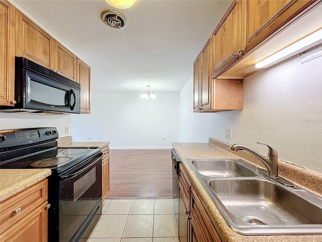 kitchen with brown cabinets, light tile patterned floors, visible vents, a sink, and black appliances