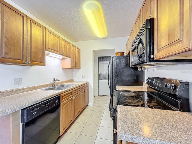 kitchen with brown cabinets, a textured ceiling, black appliances, a sink, and light tile patterned flooring