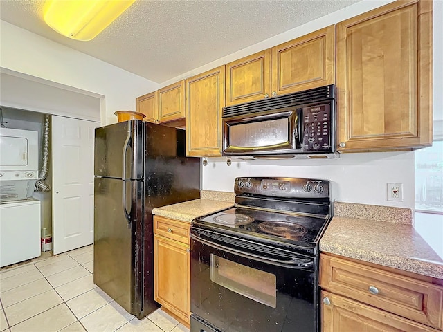 kitchen featuring light tile patterned floors, stacked washing maching and dryer, light countertops, a textured ceiling, and black appliances