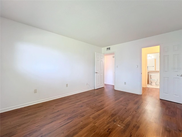 unfurnished bedroom featuring dark wood-type flooring, visible vents, and baseboards