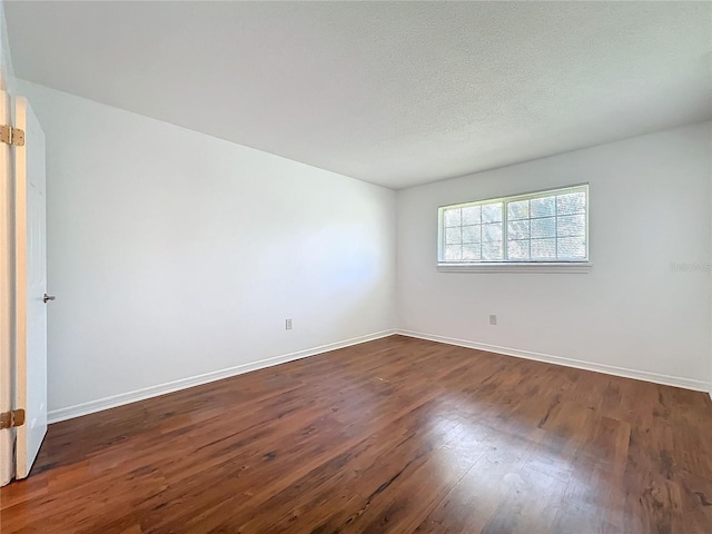 empty room featuring dark wood-style floors, a textured ceiling, and baseboards