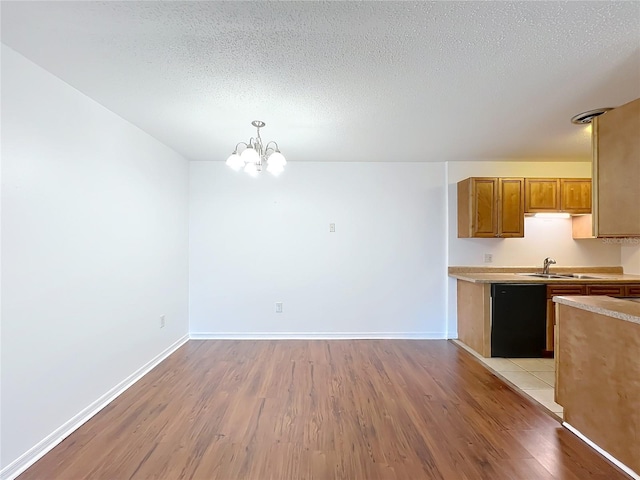 kitchen featuring light wood-type flooring, light countertops, dishwasher, and a sink