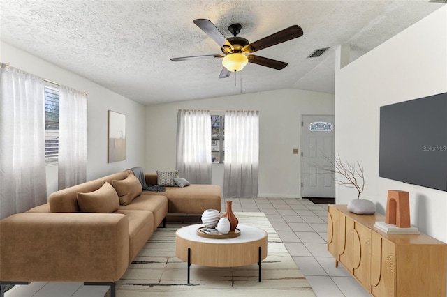 living area with vaulted ceiling, light tile patterned flooring, visible vents, and a wealth of natural light