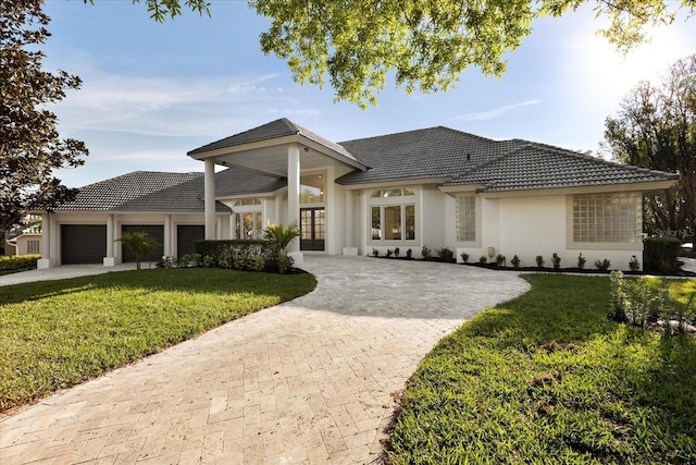 view of front of home featuring a tiled roof, decorative driveway, an attached garage, and a front yard