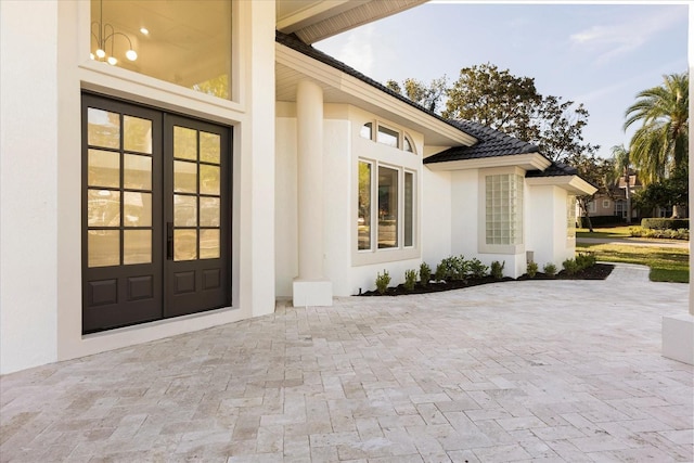 doorway to property with a tiled roof, french doors, and stucco siding