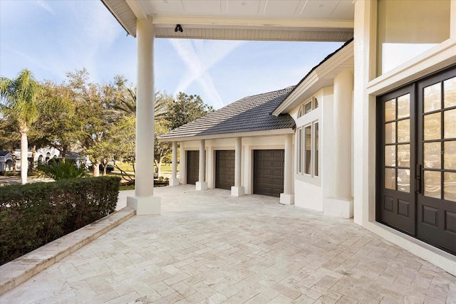 view of patio / terrace with an attached garage, decorative driveway, and french doors