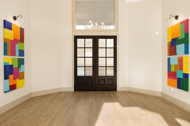 entrance foyer with french doors, wood finished floors, and baseboards