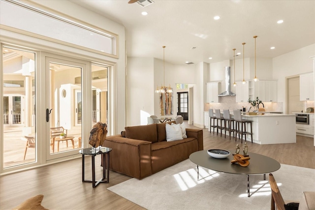 living room with light wood-style floors, recessed lighting, and an inviting chandelier