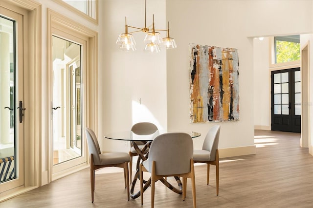 dining area featuring french doors, a high ceiling, baseboards, and wood finished floors