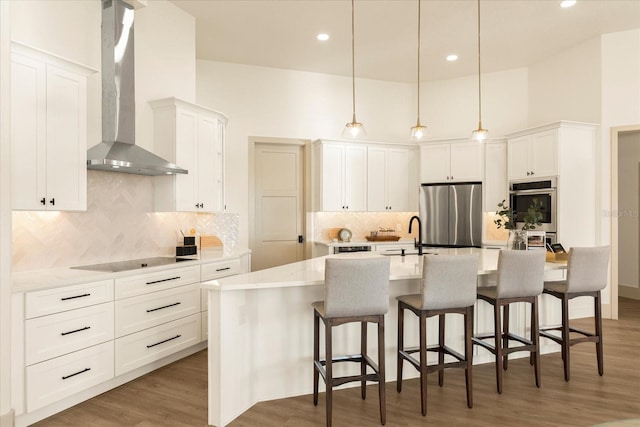 kitchen featuring stainless steel appliances, white cabinets, a high ceiling, and wall chimney exhaust hood