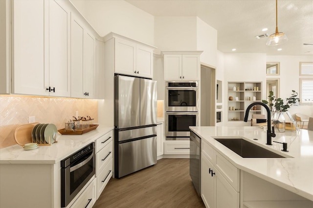 kitchen with wood finished floors, a sink, visible vents, appliances with stainless steel finishes, and tasteful backsplash