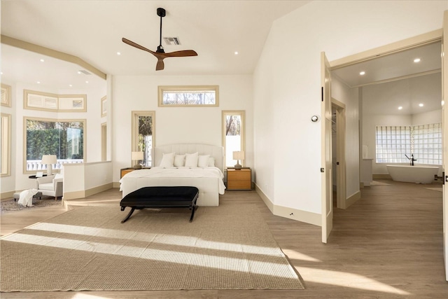 bedroom with light wood-style flooring, multiple windows, a towering ceiling, and visible vents