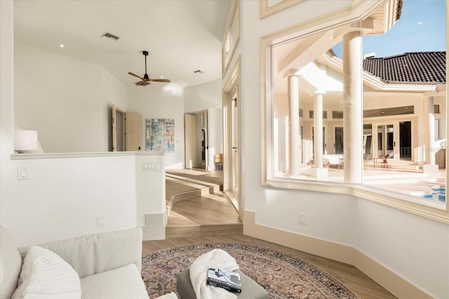 interior space featuring baseboards, visible vents, ornate columns, and wood finished floors