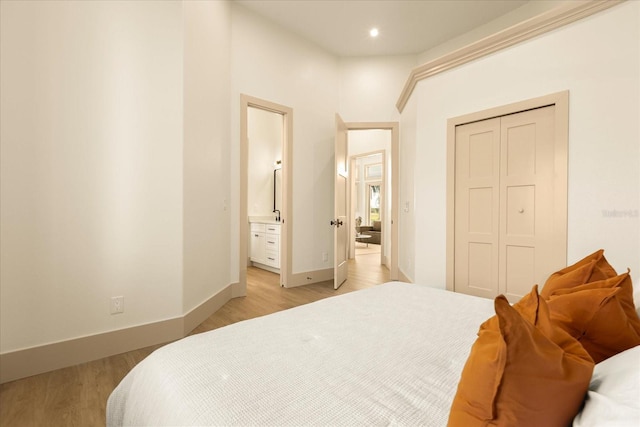 bedroom with recessed lighting, baseboards, a closet, light wood-type flooring, and ensuite bath