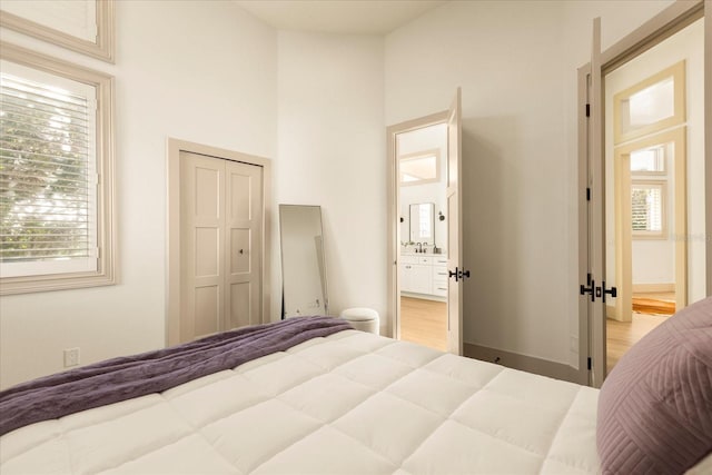 bedroom with light wood finished floors, a closet, a high ceiling, and a sink