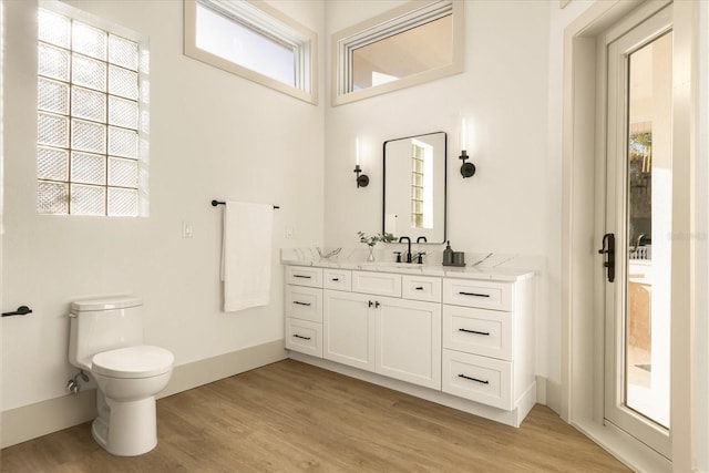 bathroom with baseboards, vanity, toilet, and wood finished floors