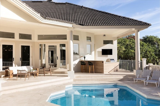 back of house featuring exterior kitchen, a patio, an outdoor living space, and a tiled roof