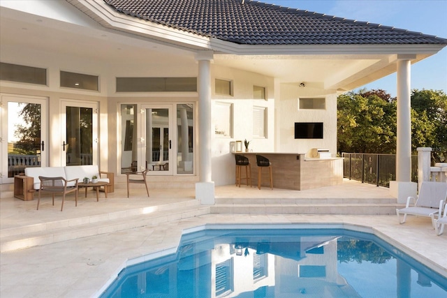 rear view of property with french doors, a tile roof, a patio, and outdoor dry bar