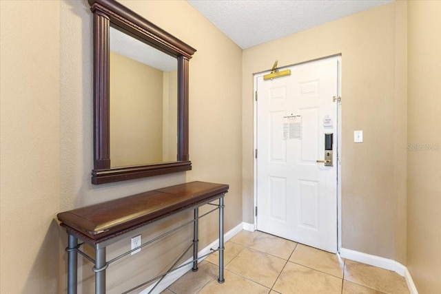 foyer featuring light tile patterned floors, a textured ceiling, and baseboards