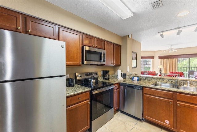 kitchen featuring stainless steel appliances, visible vents, light tile patterned flooring, a sink, and a textured ceiling