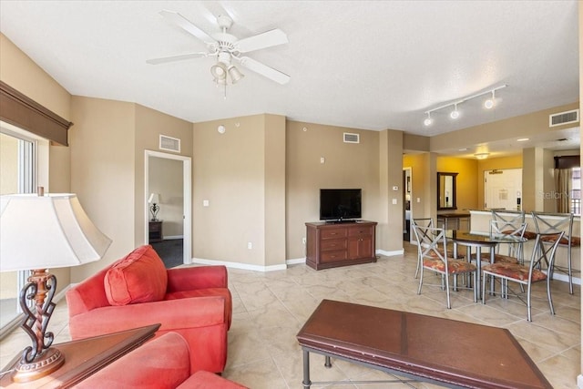 living room with ceiling fan, visible vents, and baseboards