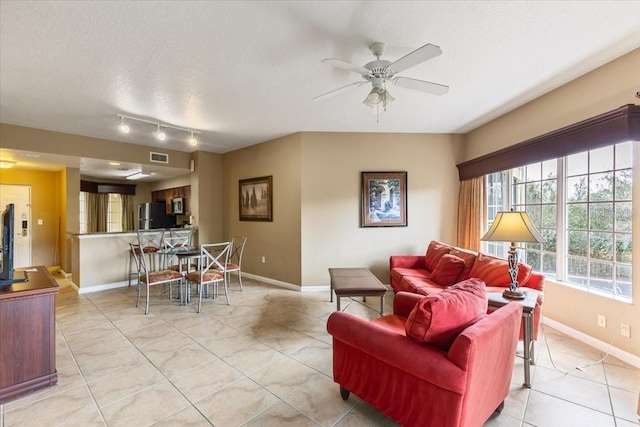 living room featuring a textured ceiling, ceiling fan, visible vents, and baseboards