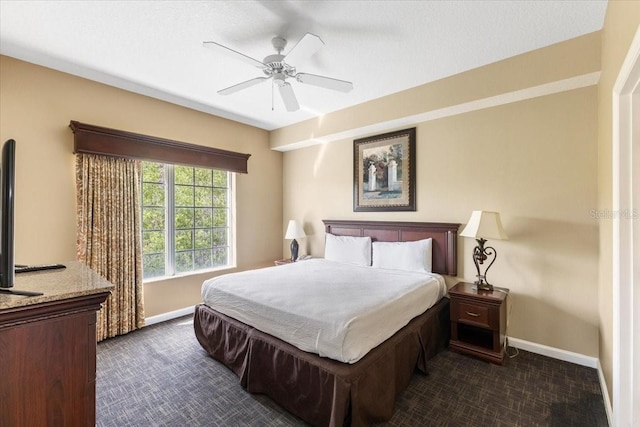 bedroom featuring dark carpet, a ceiling fan, and baseboards