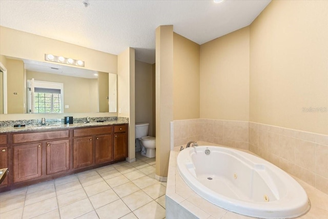 bathroom with a textured ceiling, toilet, vanity, tile patterned floors, and a tub with jets