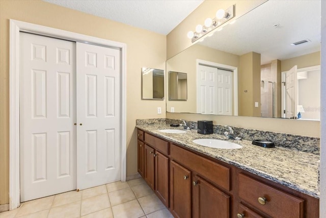 bathroom with double vanity, visible vents, a sink, and tile patterned floors