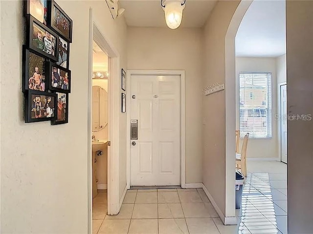 interior space featuring baseboards, arched walkways, and light tile patterned flooring