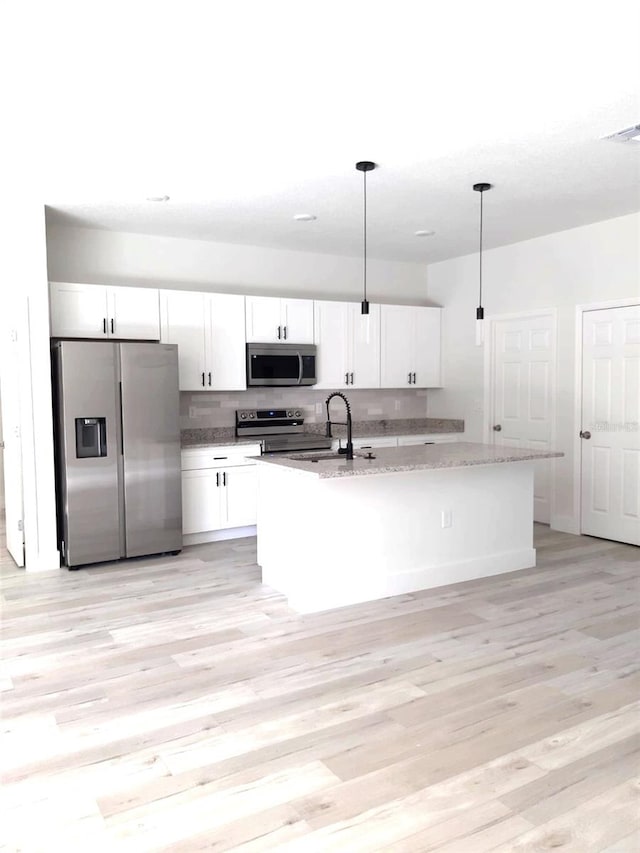 kitchen with light stone counters, white cabinetry, light wood-style flooring, a sink, and stainless steel appliances