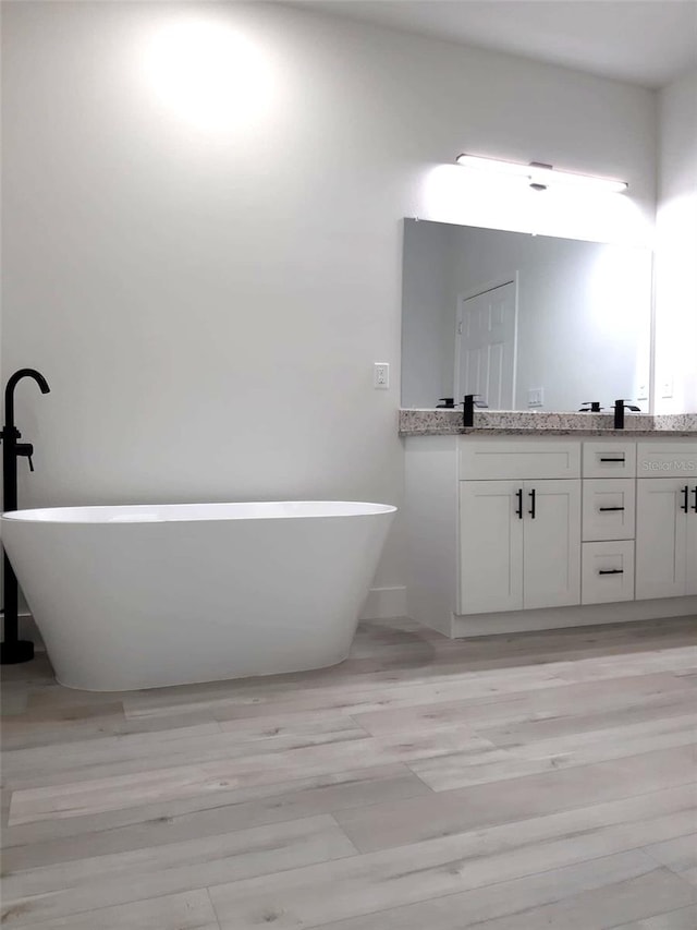 full bathroom with a soaking tub, double vanity, and a sink