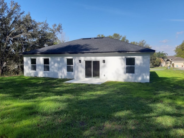 back of property featuring stucco siding, roof with shingles, a patio area, and a yard