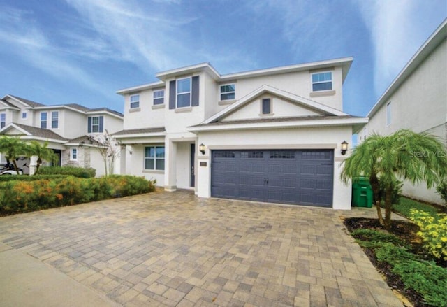 view of front facade featuring a garage, decorative driveway, and stucco siding