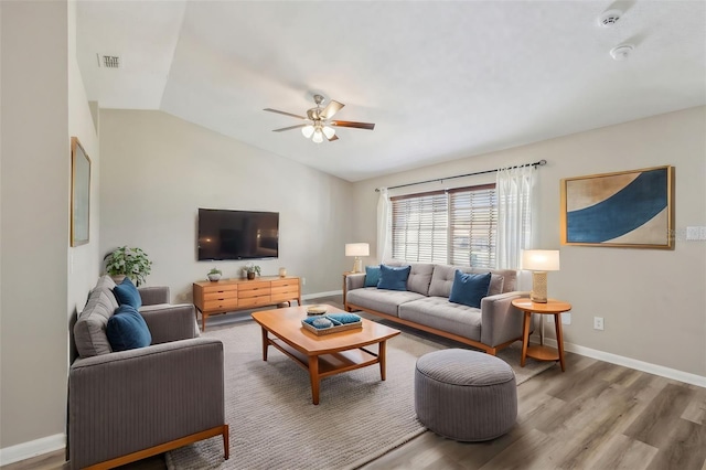 living area with vaulted ceiling, wood finished floors, baseboards, and ceiling fan