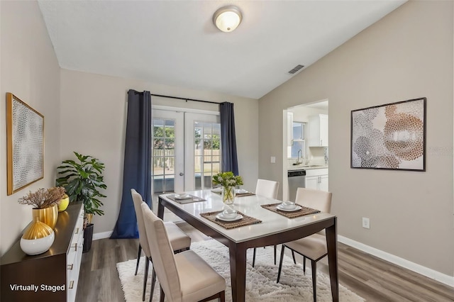 dining space with visible vents, baseboards, wood finished floors, and vaulted ceiling