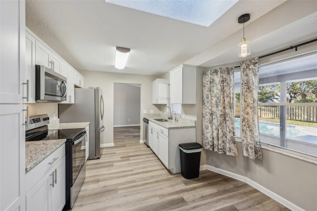 kitchen featuring a sink, stainless steel appliances, light wood-type flooring, and a textured ceiling