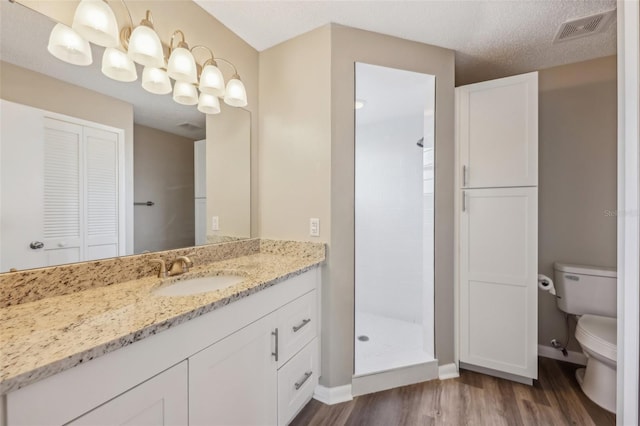 full bathroom with visible vents, a shower stall, toilet, wood finished floors, and vanity