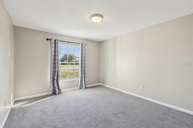 unfurnished room with baseboards, carpet, and a textured ceiling