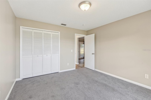 unfurnished bedroom with a closet, carpet flooring, visible vents, and baseboards