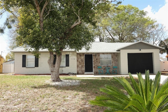 single story home featuring a front yard, concrete block siding, roof with shingles, and an attached garage