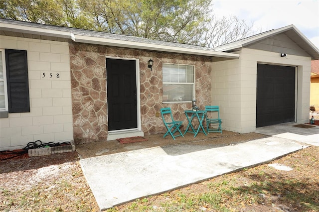 doorway to property featuring a garage and concrete block siding