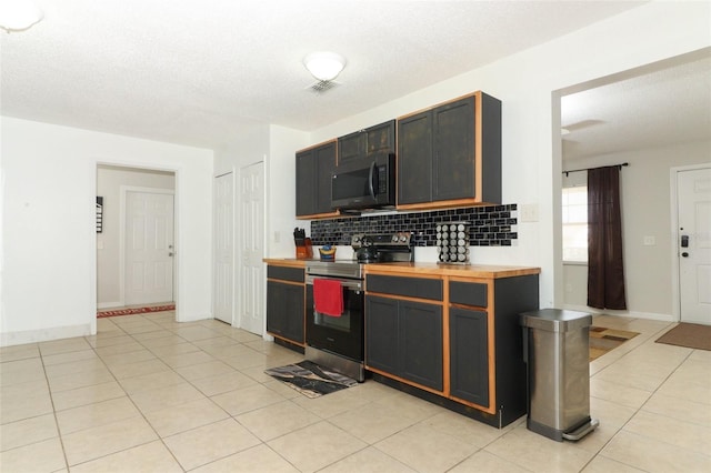 kitchen featuring tasteful backsplash, light tile patterned flooring, a textured ceiling, and stainless steel range with electric cooktop