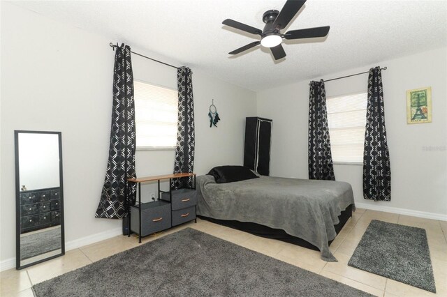 bedroom with ceiling fan, multiple windows, a textured ceiling, and light tile patterned flooring