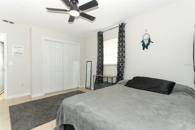 bedroom with ceiling fan, light tile patterned flooring, visible vents, baseboards, and a closet