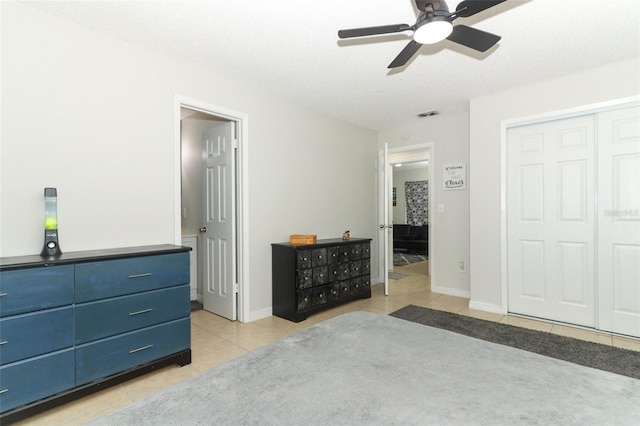 bedroom with light tile patterned floors, a closet, visible vents, ceiling fan, and baseboards