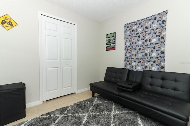 living area featuring tile patterned flooring, baseboards, and a textured ceiling