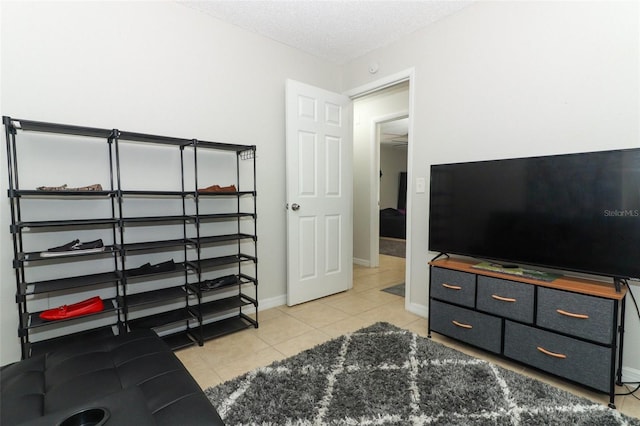 interior space featuring light tile patterned floors, a textured ceiling, and baseboards